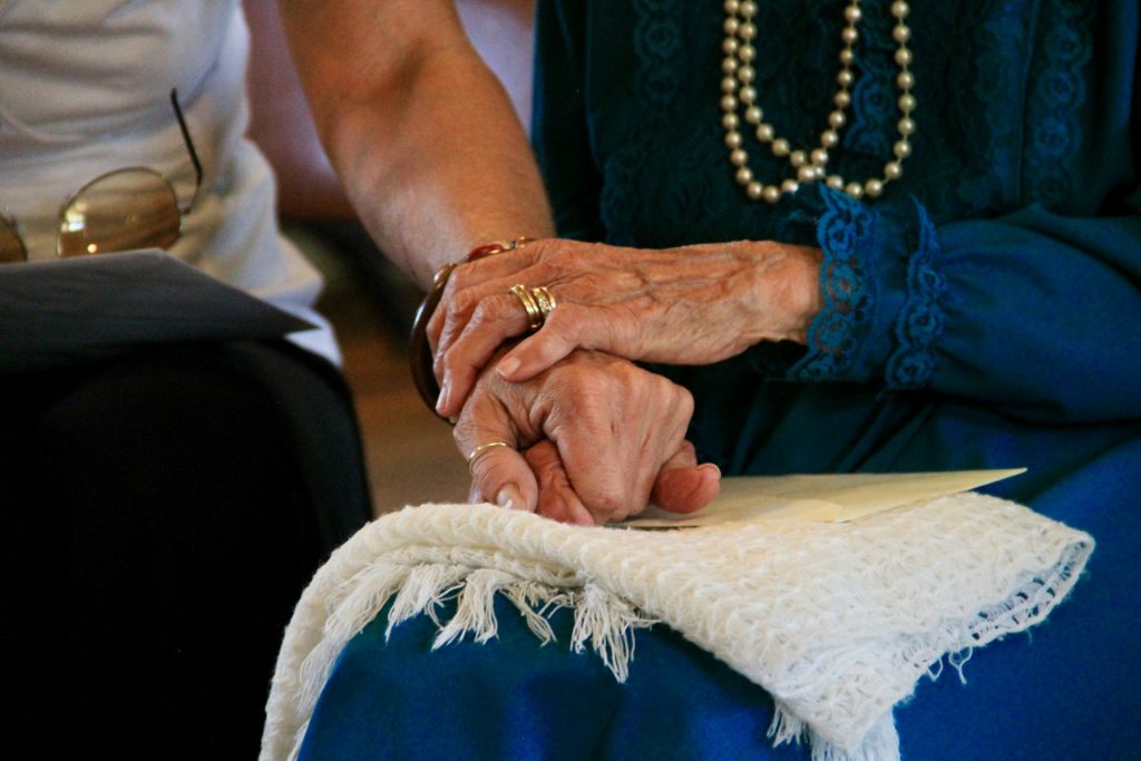 elderly lady holding hands with carer