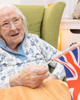 friary care resident waving flag whilst remembering d day